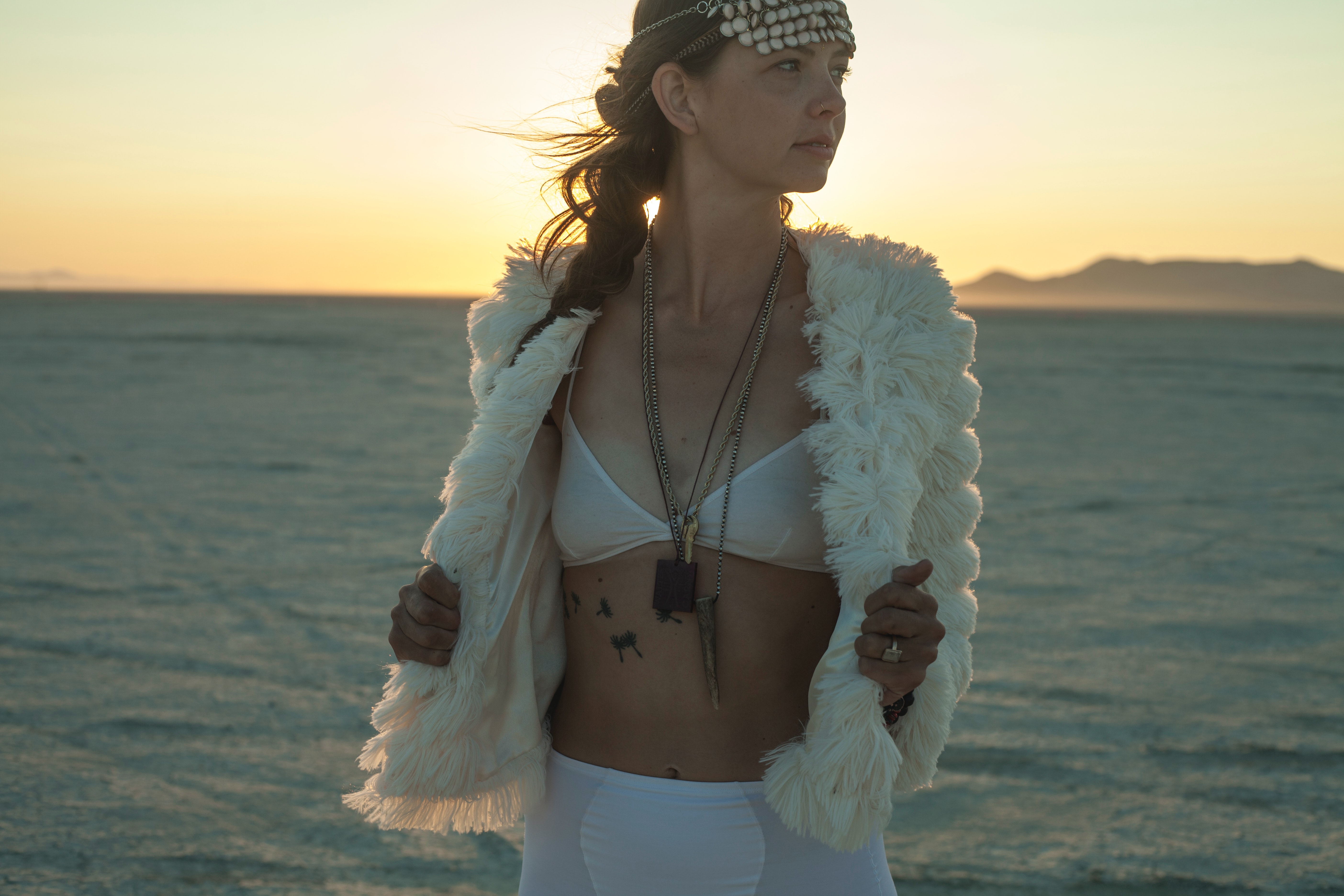 Photo by imustbedead  : https://www.pexels.com/photo/woman-in-white-fur-jacket-and-white-skirt-standing-on-beach-during-sunset-11829243/